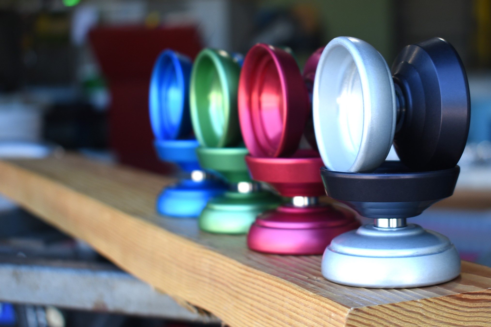 a group of One Drop Perspective yo-yos of various colors on a wood surface