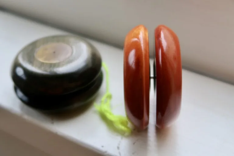 Side view of an orange wooden Doble Ariel showing its narrow axle beside a dark Ariel