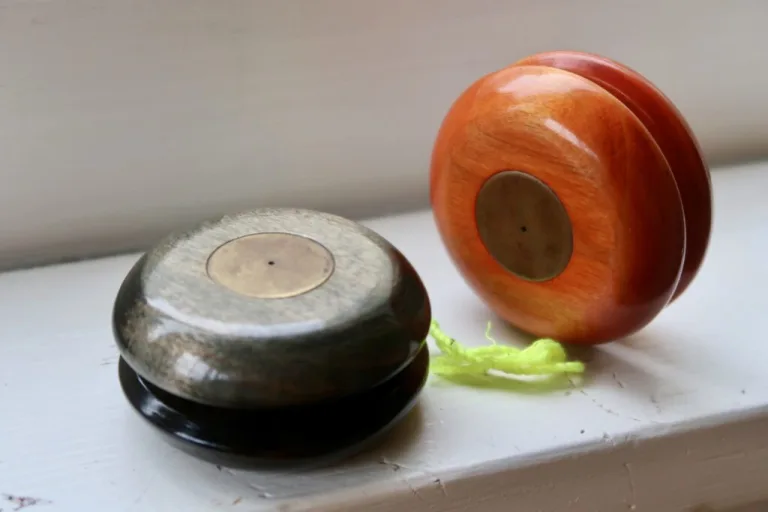 Orange and dark wooden Doble Ariel yo-yos on a windowsill