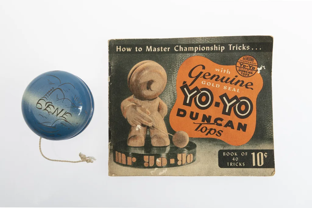Blue engraved Duncan yo-yo beside the booklet "How to Master Championship Tricks," cover showing "Mr. Yo-Yo" and the 10-cent price.