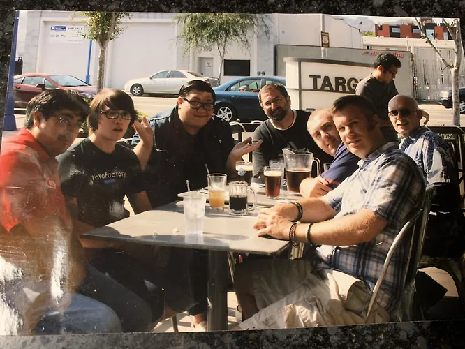 Group of yo-yo players seated around an outdoor lunch table with pitchers of beer, Southern California